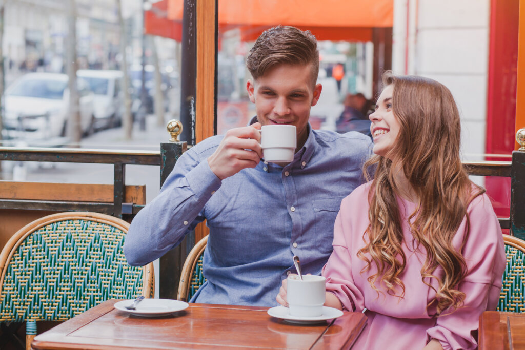 Young happy couple drinking coffee and laughing in cafe in Nice France