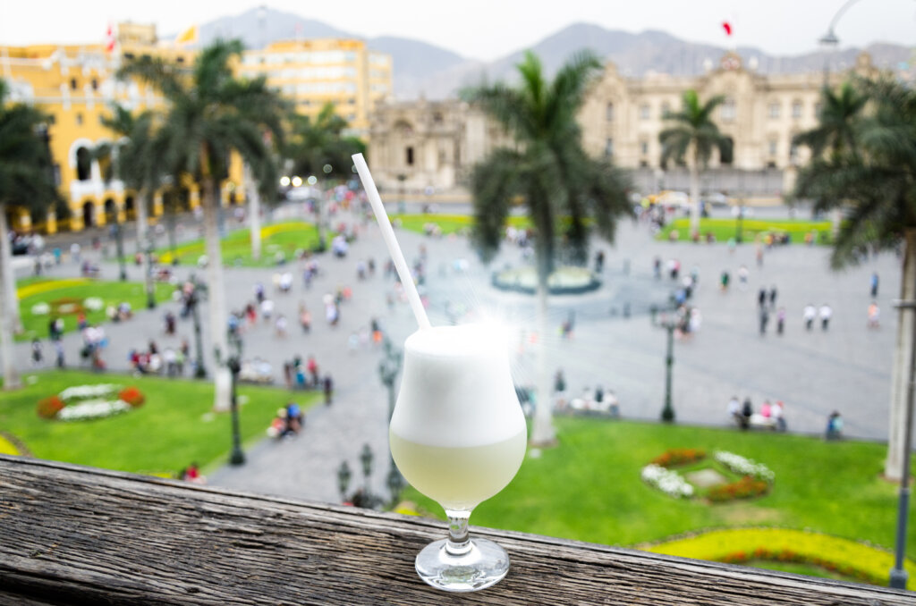 Pisco sour cocktail on ledge with Lima, Peru in blurred background. 